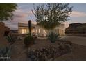 Southwestern-style home at dusk with desert landscaping featuring cacti, agave, and a rock retaining wall at 4309 S Priceless View Dr, Gold Canyon, AZ 85118