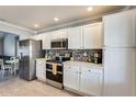 Modern kitchen features white cabinets, granite countertops, stainless steel appliances, and mosaic backsplash at 6938 W Wescott Dr, Glendale, AZ 85308