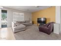 Bright living room featuring neutral walls, a comfy couch, modern media console, and direct access to the backyard at 10004 W Raymond Street St, Tolleson, AZ 85353