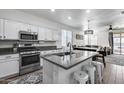 Bright kitchen featuring white cabinetry, stainless steel appliances, and a spacious granite island with bar seating at 13159 W Rowel Rd, Peoria, AZ 85383