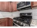 Close up of the stainless steel stove and microwave, granite countertops and tile backsplash at 141 W Jamaica Pl, Casa Grande, AZ 85122