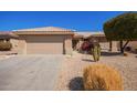 Garage and covered entry to a tan home featuring desert landscaping and a tiled roof at 16016 W Indigo Ln, Surprise, AZ 85374