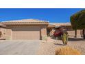 Tan home showing the garage, tiled roof, desert landscaping, and rose bush by the front door at 16016 W Indigo Ln, Surprise, AZ 85374