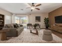 Bright living room with a ceiling fan, neutral colors, and sliding glass doors to the backyard at 2521 W Mark Ln, Phoenix, AZ 85085