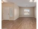 Bright living room featuring wood-look tile floors and neutral walls, with a view of the front door and window at 2521 W Mark Ln, Phoenix, AZ 85085