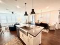 Open-concept living area with a kitchen island, hardwood floors, and lots of windows with natural light at 357 E Las Puertas Ln, Queen Creek, AZ 85140