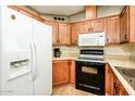 Functional kitchen featuring white refrigerator, black stove, and ample wooden cabinetry at 6161 S Oakmont Dr, Chandler, AZ 85249