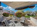 Outdoor patio space with pavers, striped chairs, decorative covering, and well manicured landscaping at 985 N Granite Reef Rd # 127, Scottsdale, AZ 85257