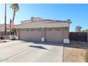 Home with a spacious three-car garage with paneled doors, desert landscaping, and clear blue skies at 12439 W Monte Vista Rd, Avondale, AZ 85392