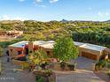 Gorgeous desert home featuring a multi-car garage, mature trees, red awnings, and beautiful landscaping at 1489 Thrasher Ln, Wickenburg, AZ 85390