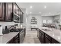 Spacious kitchen showcasing stainless steel appliances, dark cabinets, and an island with a view into the dining area at 16561 W Cielo Grande Ave, Surprise, AZ 85387