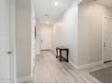 Bright hallway with light wood-look floors, white walls, white doors, and a charming wooden accent table at 21150 W Minnezona Ave, Buckeye, AZ 85396