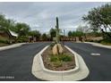 Community entrance featuring desert landscaping, stone columns, and wooden gates on a cloudy day at 31483 N 133Rd Dr, Peoria, AZ 85383