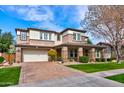 Inviting two-story home with stone accents, manicured lawn, brick driveway, and a welcoming facade at 3744 E Sierra Madre Ave, Gilbert, AZ 85296