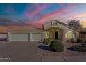 Inviting home exterior featuring a well-manicured lawn, three car garage, and a covered entryway during a colorful sunset at 630 W Madero Ave, Mesa, AZ 85210