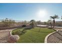 Manicured backyard featuring an artificial lawn, desert landscaping, and a private pool area, ideal for outdoor living at 7355 W Red Hawk Dr, Peoria, AZ 85383