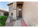 Inviting front entrance with a textured stucco wall, brick accents, and metal security door at 1119 W Heather Ave, Gilbert, AZ 85233