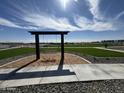 Community area features a swing set, grassy area and walking path with benches and sprinkler system at 15665 W Deanne Dr, Waddell, AZ 85355