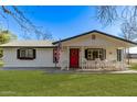 Beautiful home featuring a vibrant green lawn, white siding, and a welcoming red door at 17335 W Cheryl Dr, Waddell, AZ 85355