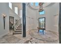 Spacious foyer with tile flooring, a decorative table, a statement column, and stairway access at 28503 N 104Th Way, Scottsdale, AZ 85262