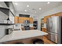 Well-lit kitchen featuring stainless steel appliances, white countertops and subway tile, wood cabinets and two barstools at 40265 N Acadia Ct, Anthem, AZ 85086