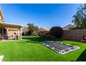 Spacious backyard with artificial turf, a covered patio, and a playset for Gathering enjoyment at 9853 W Irma Ln, Peoria, AZ 85382