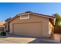 A tan two-car garage with a tile roof and desert landscaping at 9853 W Irma Ln, Peoria, AZ 85382