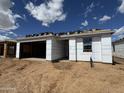 Unfinished exterior featuring an attached garage, covered entry, and material for roof installation at 15772 W Beryl Ave, Waddell, AZ 85355