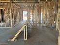 Unfinished Living room of new home construction with exposed frame, studs, and bare concrete floors at 15772 W Beryl Ave, Waddell, AZ 85355