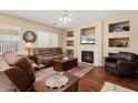 Comfortable living room with hardwood floors, a cozy fireplace, and custom built-in shelving at 16351 W Central St, Surprise, AZ 85388