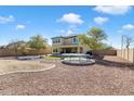 Expansive backyard with gravel landscaping, trampoline, patio, and a view of the two-story home at 17190 W Bent Tree Dr, Surprise, AZ 85387