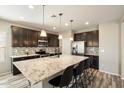 Modern kitchen features a large island with bar seating, stainless steel appliances, and dark wood cabinetry at 17190 W Bent Tree Dr, Surprise, AZ 85387