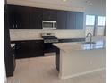 Modern kitchen featuring dark cabinetry, stainless steel appliances, and a granite-topped island at 917 W Macaw Dr, Queen Creek, AZ 85140