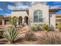 Charming single-story stucco home featuring desert landscaping, a tiled roof and a delightful arched entry at 9266 E Desert Village Dr, Scottsdale, AZ 85255