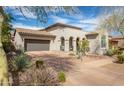 Inviting single-story stucco home showcasing desert landscaping, a tiled roof and a charming arched entry at 9266 E Desert Village Dr, Scottsdale, AZ 85255