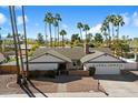 Charming single-story home featuring a brick chimney, two-car garage, beautiful desert landscaping and many palm trees at 10052 N 77Th St, Scottsdale, AZ 85258
