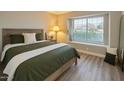 Cozy bedroom with a large window, stylish decor, wood-look flooring, and comfortable furnishings at 1016 E Utopia Rd, Phoenix, AZ 85024