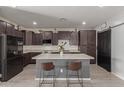 Stylish kitchen featuring a center island with seating, dark cabinets, modern appliances, and a pantry at 17583 W Paraiso Dr, Surprise, AZ 85387