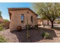 View of the home's side showing neutral stucco, desert landscaping, and decorative window accents at 19405 W Oregon Ave, Litchfield Park, AZ 85340