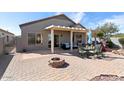 Beautiful backyard with a covered patio, fire pit, seating area, and well-maintained landscaping at 15876 W Alpine Ridge Dr, Surprise, AZ 85374