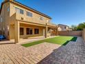 A spacious backyard features a covered patio, artificial turf, and brick accents, perfect for outdoor living at 16247 W Desert Mirage Dr, Surprise, AZ 85379