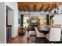 Open-concept living and dining area featuring a stone fireplace, wood beam ceiling, and tiled flooring at 2548 E Vermont Ave, Phoenix, AZ 85016