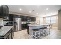 Modern kitchen with dark cabinets, granite countertops, stainless steel appliances, and breakfast bar seating at 30324 W Crittenden Ln, Buckeye, AZ 85396