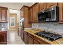 This kitchen features granite countertops, a gas cooktop, dark wood cabinets, and stainless steel appliances at 42988 W Misty Morning Ln, Maricopa, AZ 85138