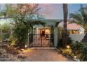 Charming gated entrance with lush greenery, accent lighting, and a pergola offering a welcoming approach to the home at 7451 E Long Rifle Rd, Carefree, AZ 85377