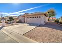 Landscaped front yard of a beige home showcasing desert landscaping and a concrete driveway at 9437 E Champagne Dr, Sun Lakes, AZ 85248