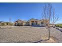 Tan single story desert home with a three car garage and gravel front yard at 1727 E Hidalgo St, Apache Junction, AZ 85119