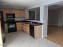 Spacious kitchen featuring black appliances, light wood cabinets, black countertop, and tile flooring at 5501 S Dove Crk Crk, Buckeye, AZ 85326