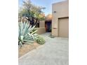 A desert-landscaped front entrance with a wood door and two-car garage is warm and inviting at 9110 E Clubhouse Ct # 639, Scottsdale, AZ 85262