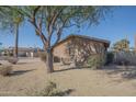 A charming residence with desert landscaping, mature shade trees, and a cozy bench along the side at 13134 N 20Th Ave, Phoenix, AZ 85029